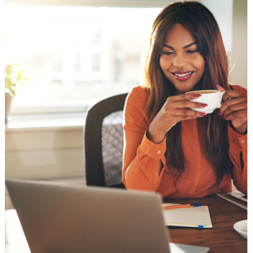 Woman sipping on coffee looking at her laptop screen
