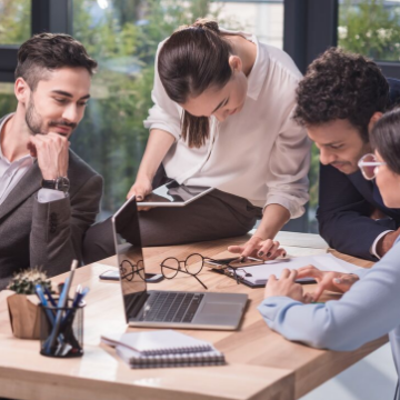 four work colleagues huddled around a laptop
